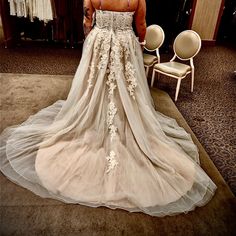 a woman in a wedding dress looking at herself in the mirror with her back to the camera