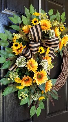 a wreath with sunflowers and greenery on the front door