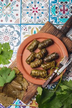 stuffed grape leaves on a plate with a knife and fork - stock photo - images