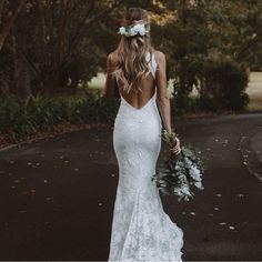 a woman in a wedding dress walking down the street with her back to the camera