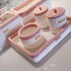 four crocheted baskets with lids and handles on a countertop next to other items