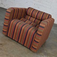 an orange and blue striped chair sitting in front of a white brick wall on concrete floor