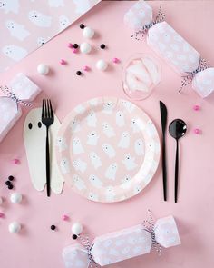 a pink table setting with black and white utensils, napkins, and paper plates