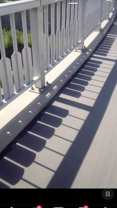 the shadow of a person riding a skateboard is cast on a bridge with white railings