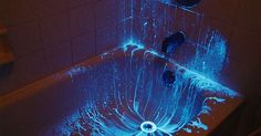 a bathtub that has some blue lights on the side and water running down it