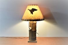 a lamp with a bird on it sitting on a table next to a white wall