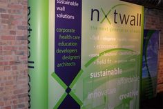 a green and purple banner next to a brick wall with the words nxttwall on it