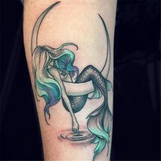 a mermaid tattoo on the leg of a woman with a crescent moon and fish tail