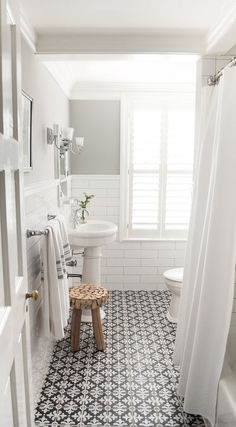 a white and blue tiled bathroom with a stool in the corner next to the shower