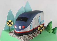 a cake shaped like a train on the tracks with trees and rocks in the foreground