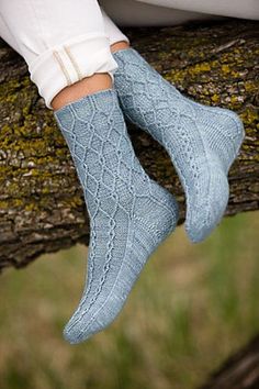 a woman's legs in blue socks and white pants sitting on a tree branch