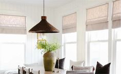 a living room filled with furniture and windows covered in roman blind shades on top of them