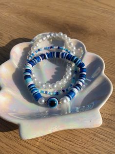 two bracelets are sitting on top of a white shell with blue and white beads