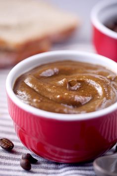 two red bowls filled with peanut butter on top of a checkered table cloth next to toast