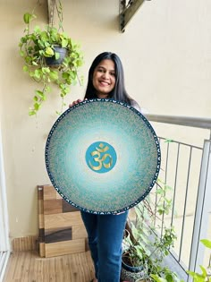 a woman holding up a blue and gold plate with an om symbol on it