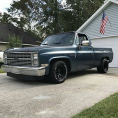 a truck parked in front of a house with an american flag on the side of it