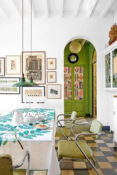 a dining room with green doors and pictures hanging on the wall, along with a checkered table cloth