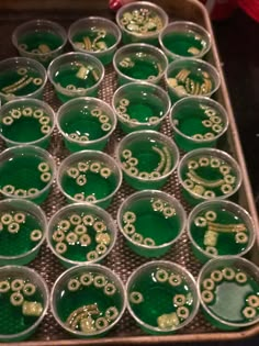 green and gold cupcakes in plastic cups on a tray