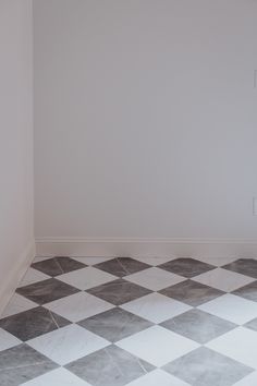 an empty room with a checkered floor and white walls