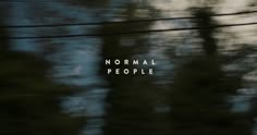 the words normal people are written in white on a blurry image of trees and telephone wires