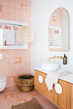 a bathroom with pink tiles and white fixtures, including a wooden sink vanity and mirror