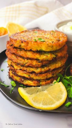 a stack of crab cakes on a plate with lemon wedges