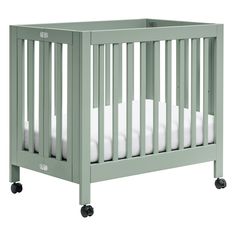 a green crib with white sheets on the bottom and side rails, in front of a white background