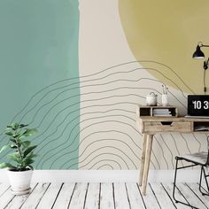 a desk with a clock on it in front of a wall painted with an abstract design