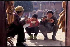 three people sitting on a bench eating food