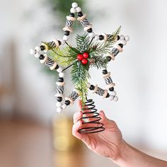 a hand holding a christmas ornament in the shape of a snowflake