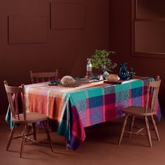 the table is covered with colorful cloths and place settings for two people to sit at