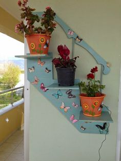 three potted plants sitting on the side of a wall next to a stair case