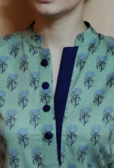 a close up of a person wearing a green shirt with blue flowers on the front