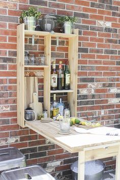 an outdoor table with pots and pans on it, next to a brick wall