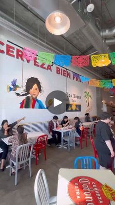 people sitting at tables in a restaurant with colorful flags hanging from the ceiling above them