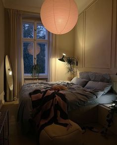 a bed room with a neatly made bed next to a large window and a lamp