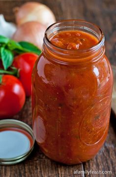 a jar filled with tomato sauce next to garlic and tomatoes