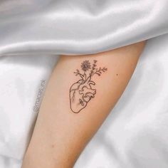 a small heart tattoo with flowers on the arm