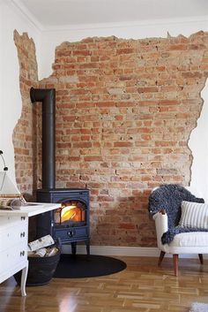 a living room with an old brick wall and wood burning stove in the corner,