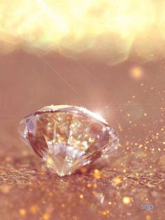 a diamond sitting on top of a table next to some gold sparkles in the background