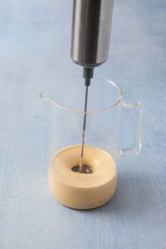 a glass coffee pot with a wooden base and handle on a blue tableclothed surface