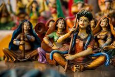 figurines of people sitting on the ground with one holding a stick and another kneeling down