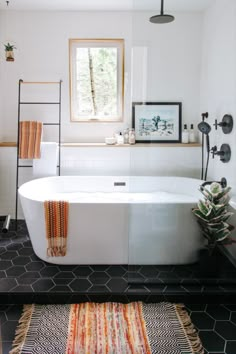 a white bath tub sitting in a bathroom next to a window