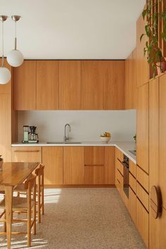 a kitchen with wooden cabinets and white counter tops next to a dining room table in front of a window