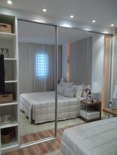 a bedroom with mirrored closet doors and two beds