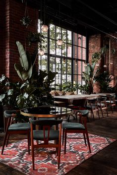 an indoor dining area with tables, chairs and potted plants