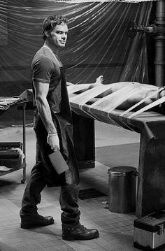 black and white photograph of a man standing in front of a table with an object on it