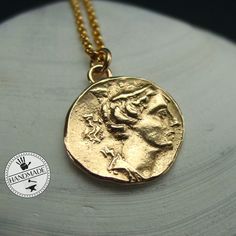 "Handmade birthing goddess Artemis necklace, reproduction of an ancient coin, perfect for fans of Percy Jackson. Artemis is the goddess of the hunt, moon, hills, forests, the wild animals and birthing. She is the twin sister of Apollo. On this rare coin she is represented with her bow poking from her shoulder. - Handmade reproduction of a Greek coin from 258-202 BC.  - Solid yellow bronze also called jeweler gold bronze coin. - One sided. - The charm is about 7/8\" - Soldered eyelet on top - 14k Goddess Style Coin Pendant Necklace, Ancient Style Brass Necklace With Coin Pendant, Ancient Bronze Necklace With Coin Pendant, Ancient Style Bronze Necklace With Coin Pendant, Ancient Coin Necklace As Gift, Ancient Style Pendant Necklaces, Ancient Style Coin Necklace With Round Pendant, Ancient Style Coin Pendant Necklace For Gift, Ancient Style Round Pendant Coin Necklace