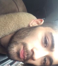 a young man laying on top of a bed next to a teddy bear in his lap