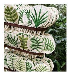 woven baskets with green leaves on them are hanging from a rack in a garden area